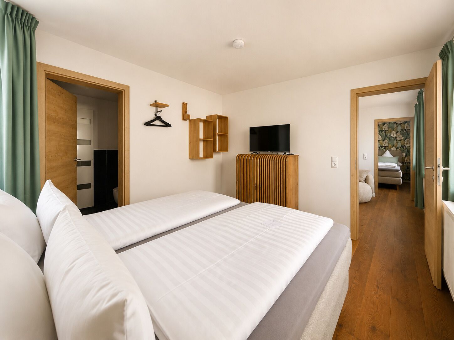 A hotel room with a bed, a television, a wardrobe, and a bathroom visible through an open door.