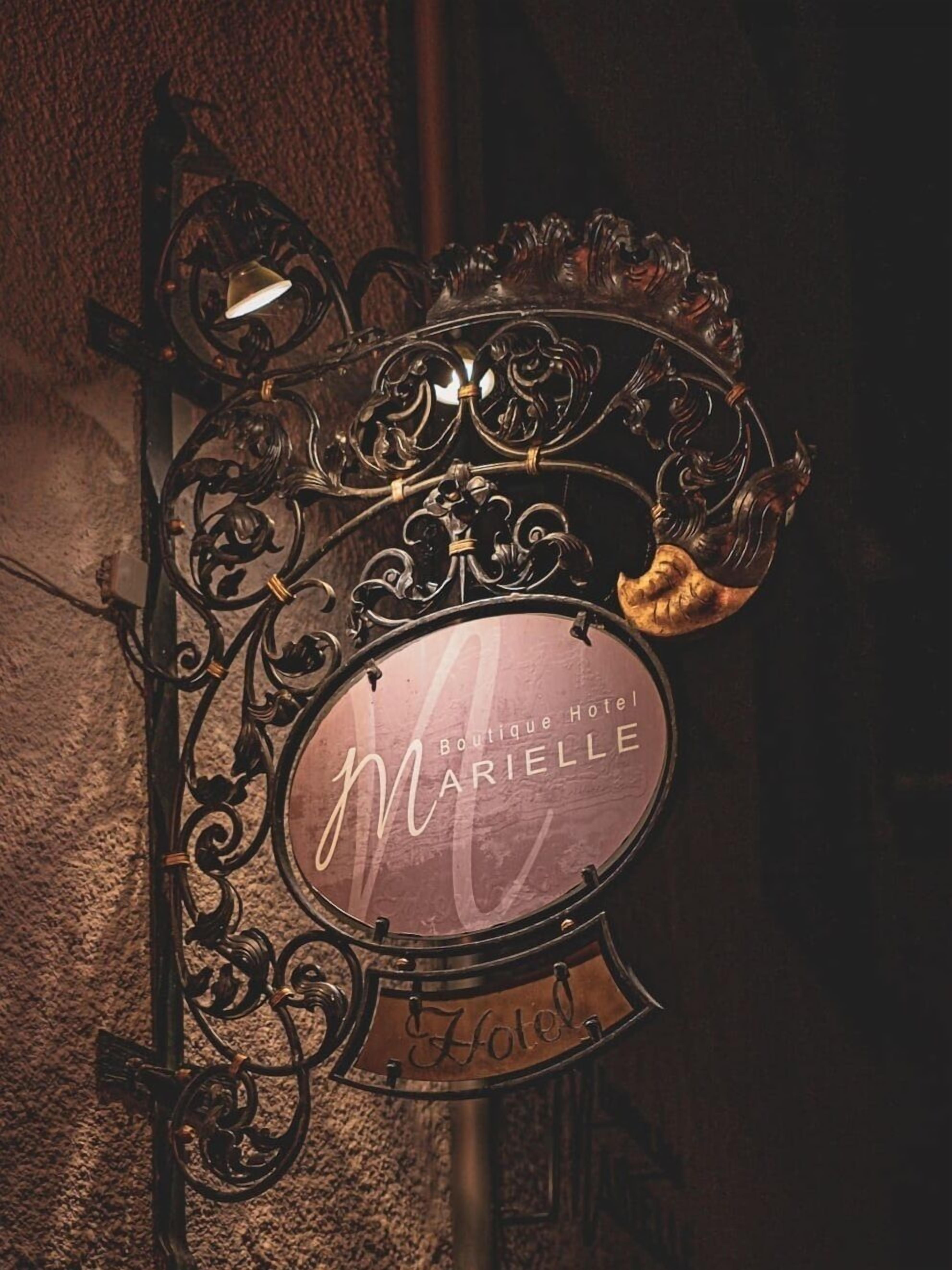 Placa do Hotel Marielle Boutique, com detalhada ferragem e um sino.