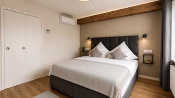 Un dormitorio con cama, mesitas de noche, aire acondicionado de pared, luz de techo y una viga de madera sobre la cama.