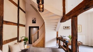 Un interior espacioso con un banco de madera, una escalera y un colgador de luz.