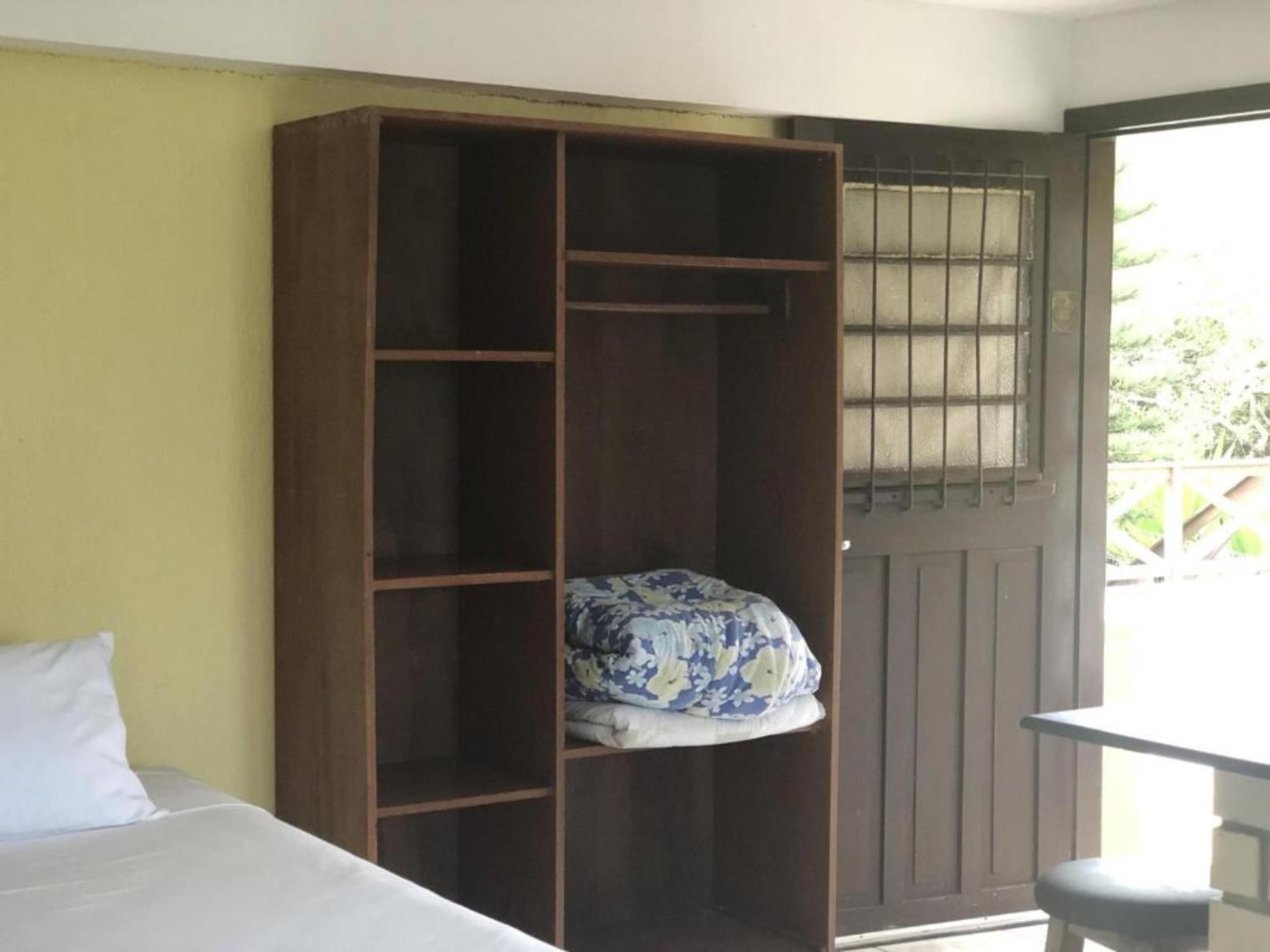 A room with a bed, a wooden wardrobe, and a table.