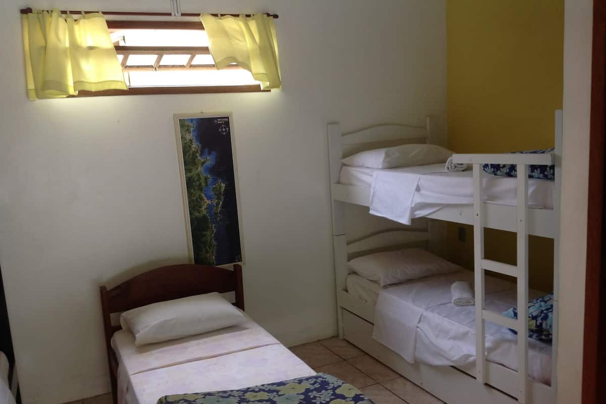 Una habitación pequeña y ordenada con una cama individual, una litera y un mapa en la pared.