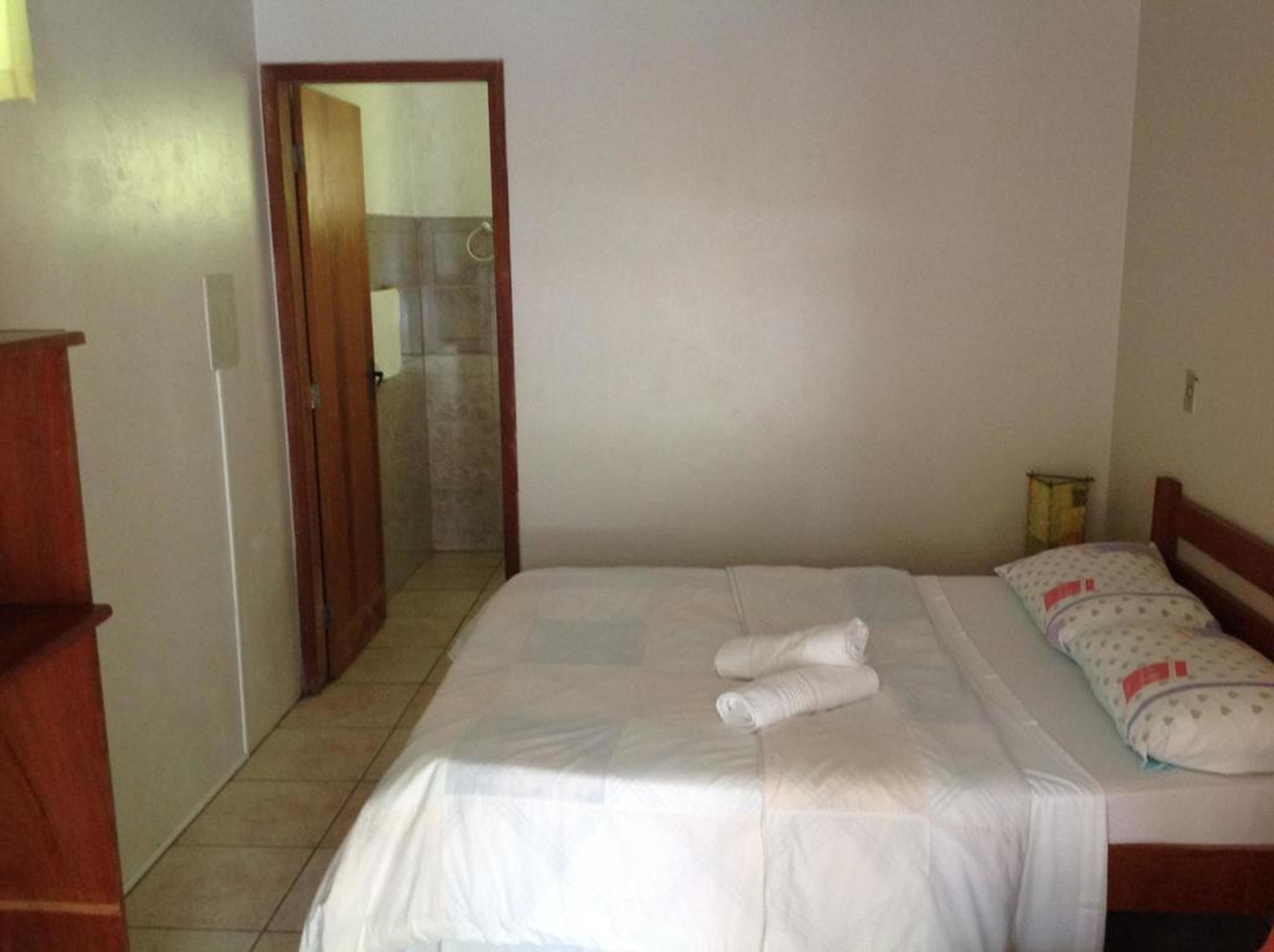 A bedroom with a bed, a wooden nightstand, and a door leading to a bathroom.