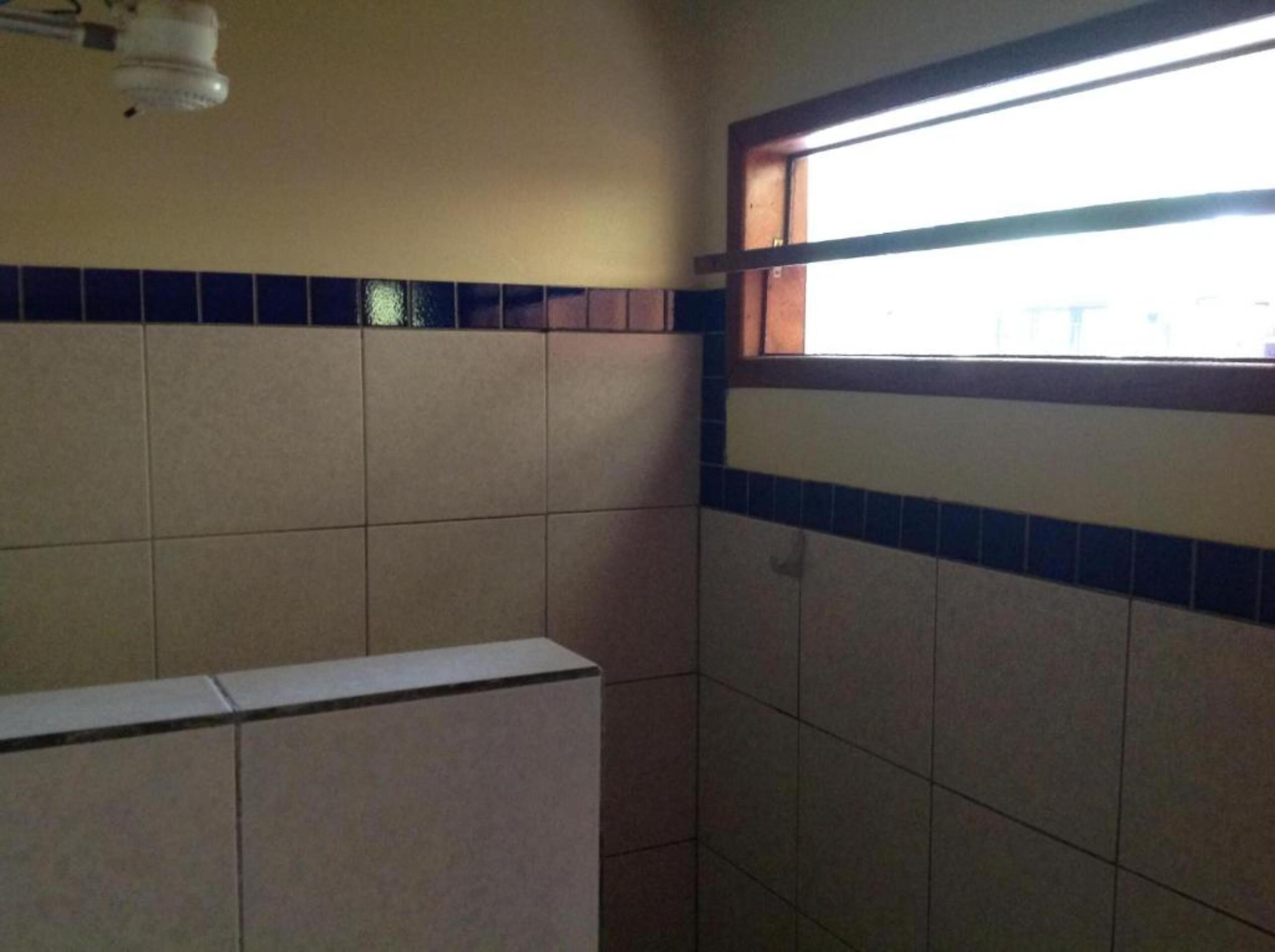 A bathroom with tiled walls, a window, and a ceiling light fixture.