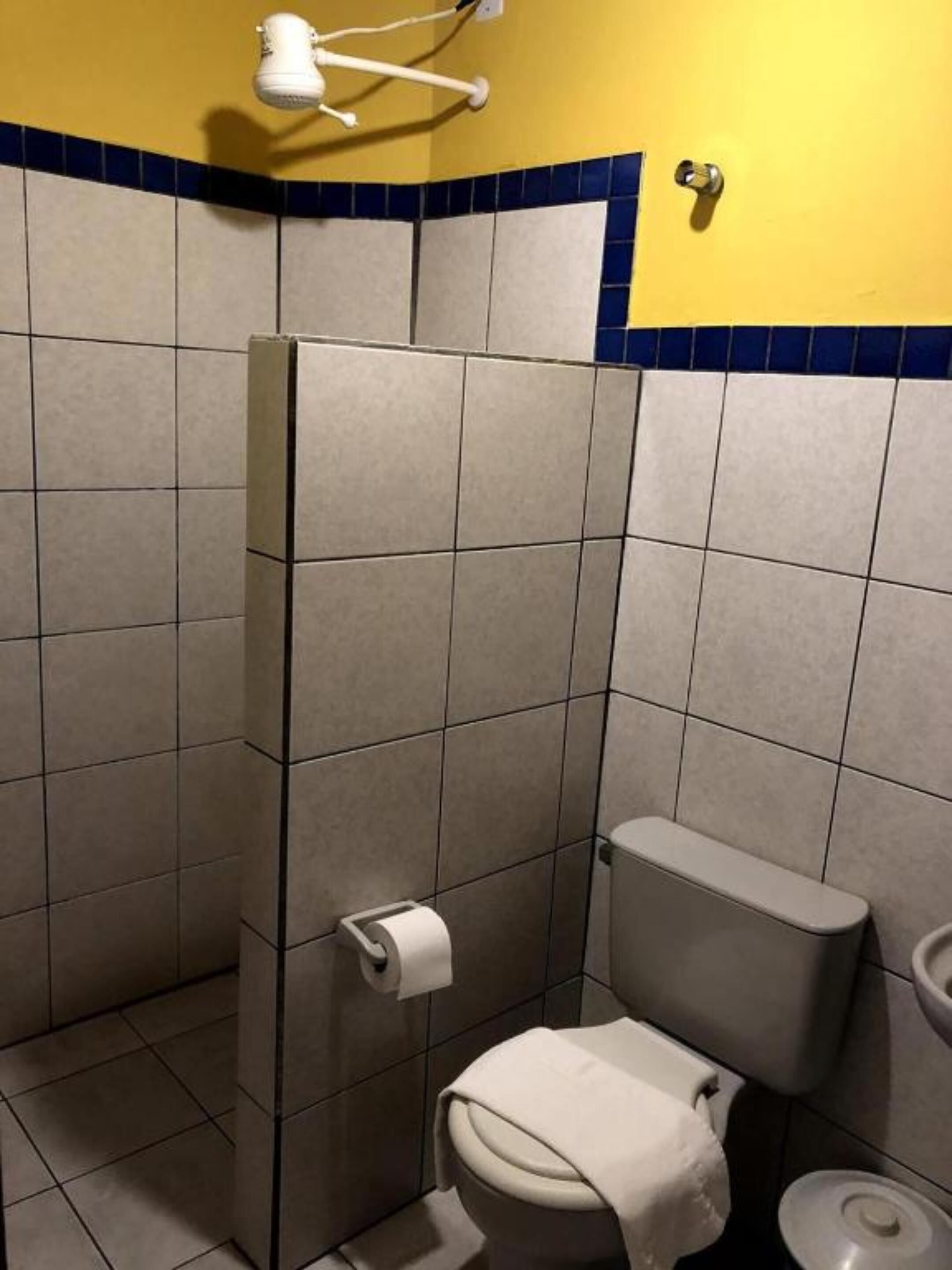 Un baño pequeño con azulejos, un inodoro, un perchero para toallas y un dispensador de servilletas de papel.