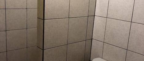 Un baño pequeño con azulejos, un inodoro, un perchero para toallas y un dispensador de servilletas de papel.