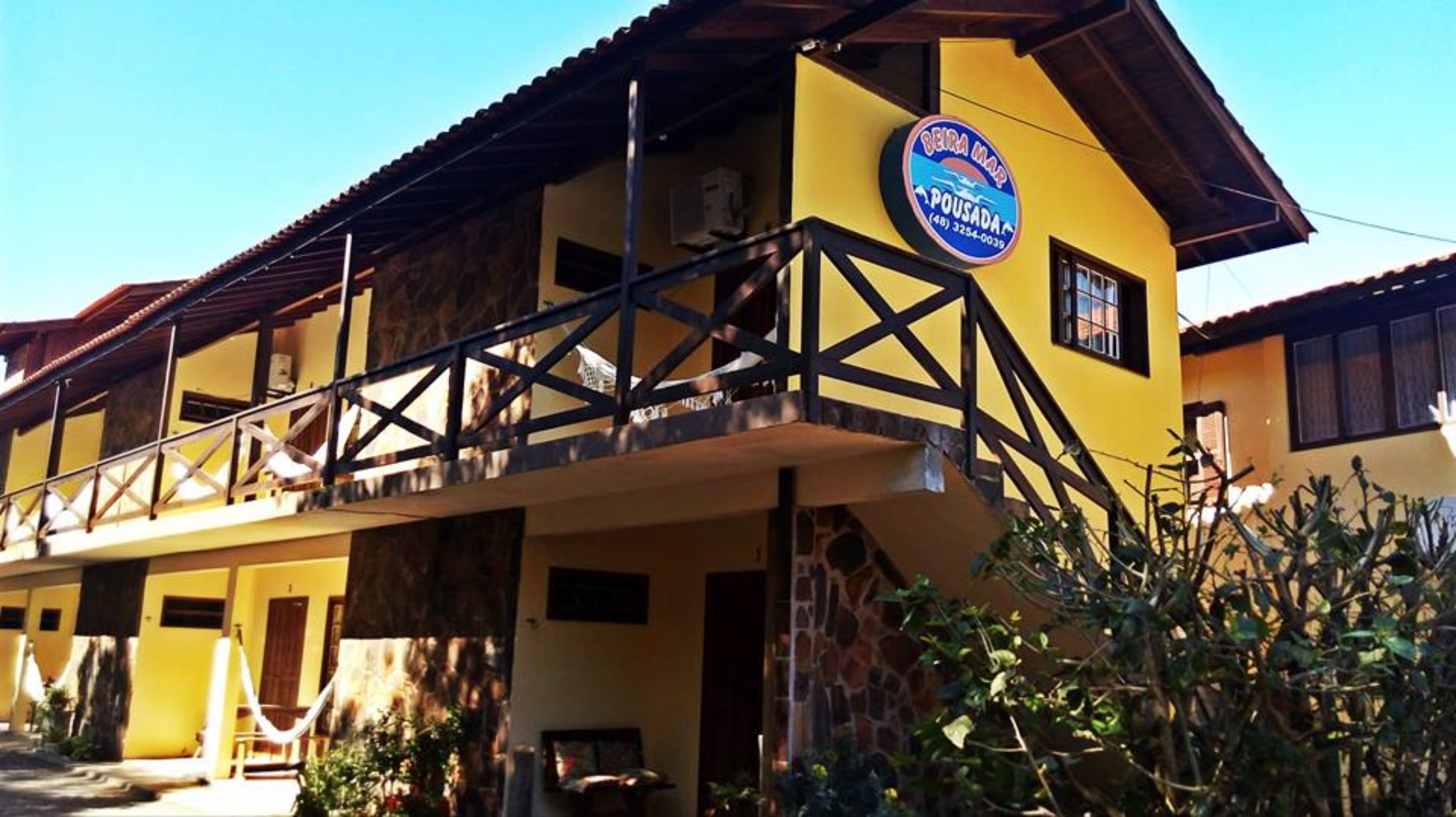 Um edifício amarelo com uma placa que diz 'Beira Mar Pousada'.