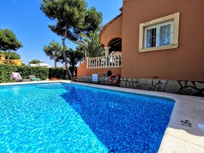 Une piscine à l’eau d’un bleu cristallin, entourée d’un mur de pierre et d’une terrasse en bois.