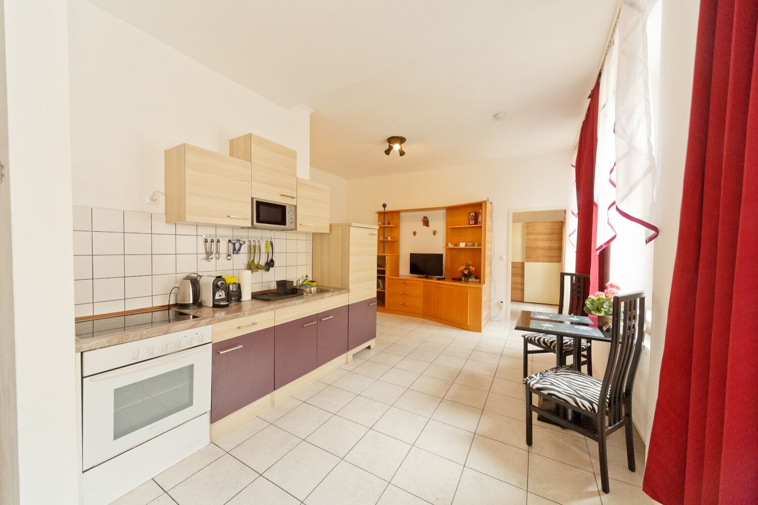 A modern kitchen with a dining area, featuring a microwave, kettle, and various utensils.
