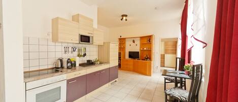 A modern kitchen with a dining area, featuring a microwave, kettle, and various utensils.