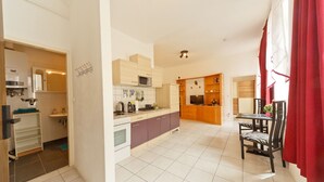A compact kitchen with a microwave, stove, and cabinets. There is a dining area with a table and chairs. - Apartment No. 14 in Vienna near Schönbrunn/Westbahnhof | Keyless Check-In (Rudolfsheim-Fünfhaus)