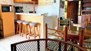 Une cuisine compacte équipée d’un four à micro-ondes, de tabourets et d’une table à manger avec des chaises.