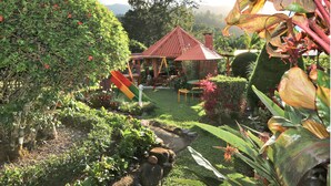 Un jardin agrémenté d’un kiosque à toit rouge, d’une végétation luxuriante et d’un petit étang.