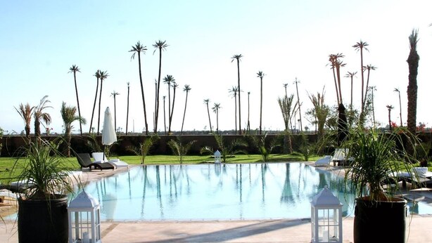 A swimming pool with palm trees, lounge chairs, and white lanterns. - Villa Rayane Marrakech (6rooms-14persons) (Marrakech)