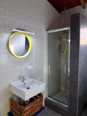 A bathroom with a white sink, a mirror with a yellow frame, and a glass shower enclosure.