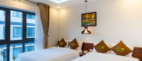 A hotel room with two beds, a large window with curtains, a painting on the wall, and a balcony with a railing.
