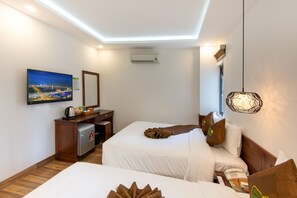 Une chambre d’hôtel avec deux lits, un bureau doté d’un réfrigérateur, un téléviseur à écran plat fixé au mur et un luminaire suspendu.