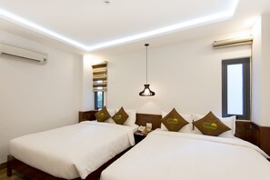 Une chambre d’hôtel avec deux lits, un luminaire au plafond, un appareil de climatisation et une fenêtre.