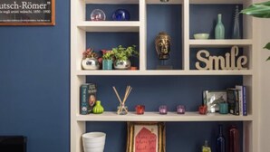 Een boekenplank met diverse decoratieve objecten, waaronder boeken, een Boeddha-beeldje en een bordje met de tekst 'Smile'.