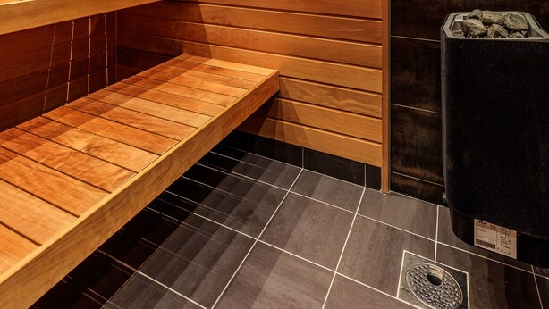 A sauna with wooden benches and a black wall. - Fjällstugan (Bruksvallarna)