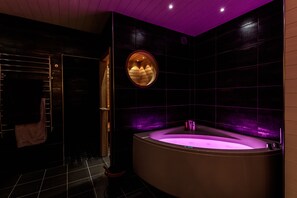 A modern bathroom with a freestanding bathtub, a circular mirror, and a towel rack. - Fjällstugan (Bruksvallarna)