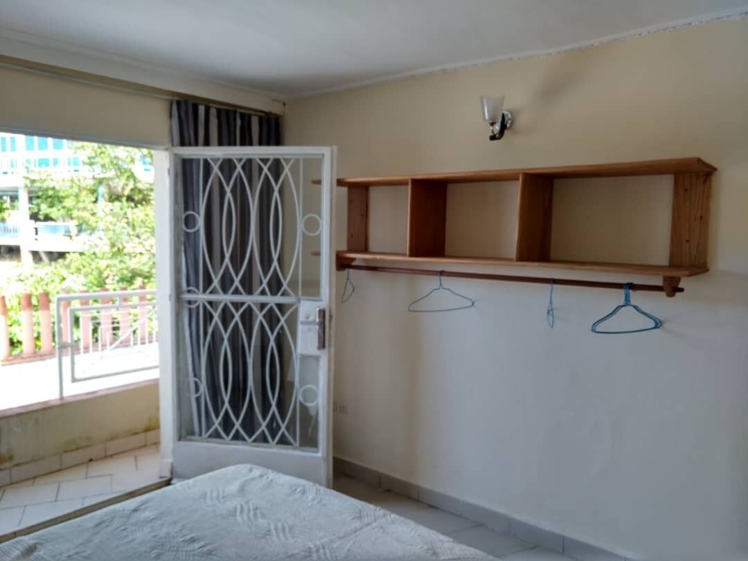 A bedroom with a bed, a wooden shelf, and a balcony door.