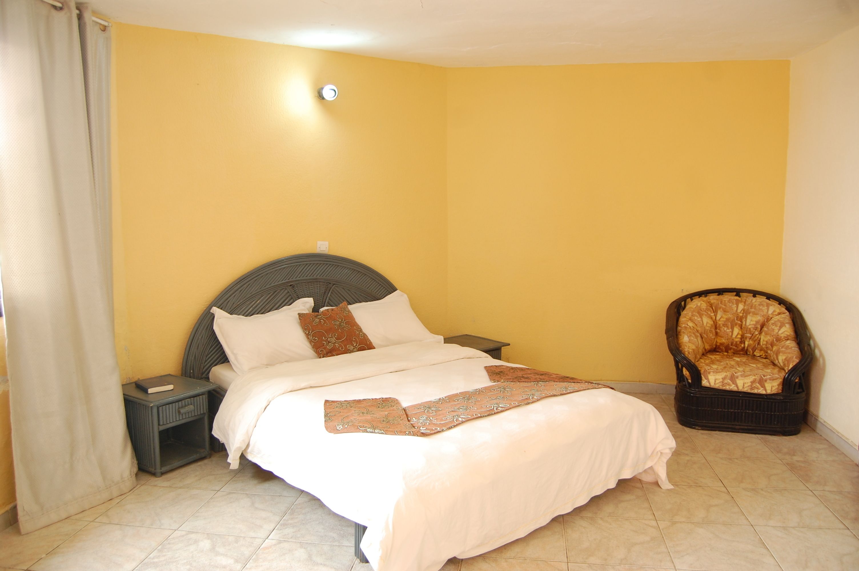A bedroom with a bed, nightstands, a chair, and a curtain.