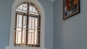 Una habitación con un amplio ventanal de arco, una escalera con barandillas negras y un cuadro abstracto enmarcado en la pared.