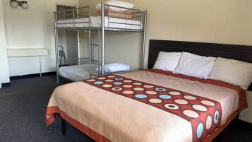 Habitación de hotel con literas, una cama individual, una colcha estampada y una lámpara fijada a la pared.