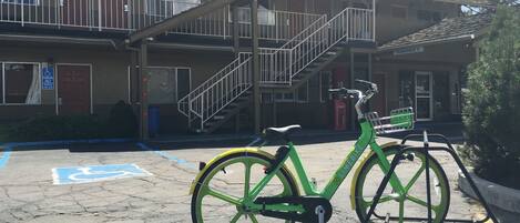 A green bicycle parked in front of a building with a staircase leading to an upper level.