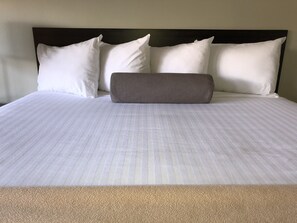 A neatly made bed with white linens and a single gray pillow. - Hotel Elevation (South Lake Tahoe)