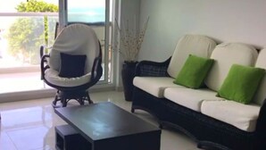 A living room with a white sofa, a black armchair, and a black coffee table. - Apartamento Familiar (San Andrés)