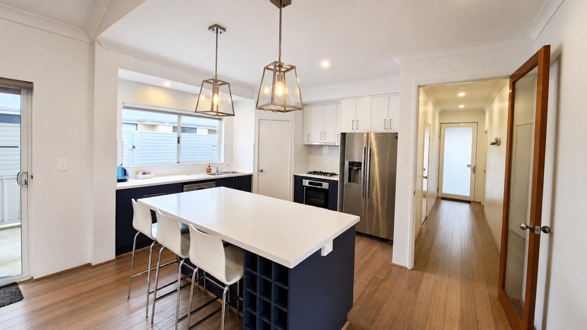 A modern kitchen with a central island, stainless steel appliances, and pendant lighting.