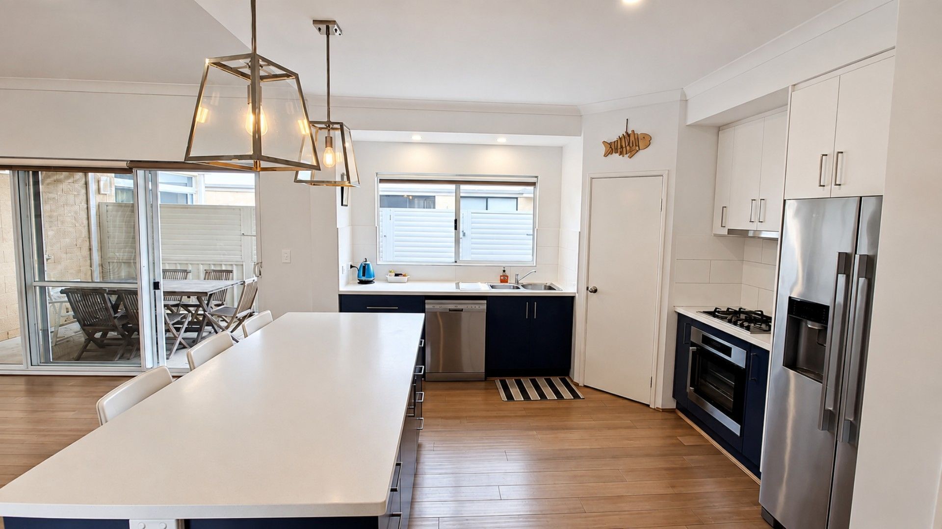 A modern kitchen with a central island, stainless steel appliances, and a dining area with a view.