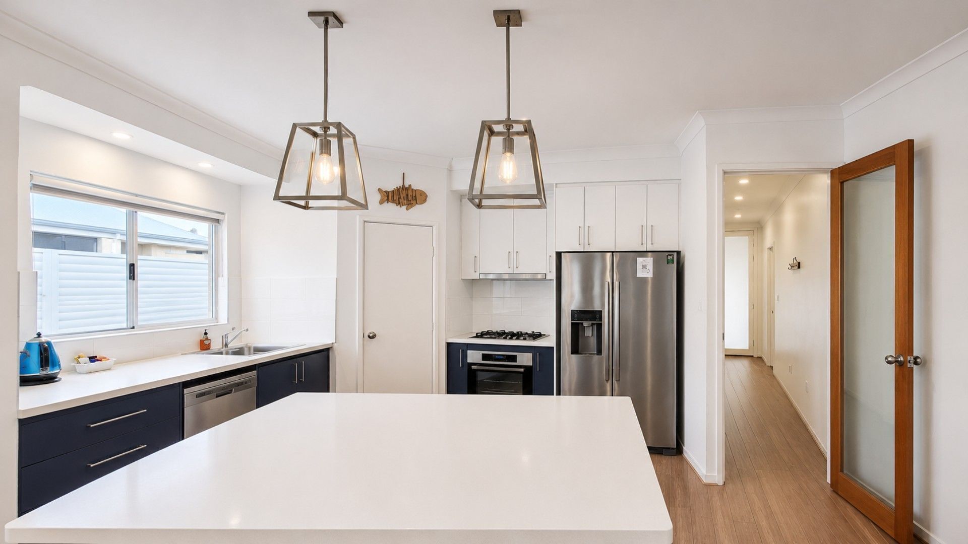 Una cucina moderna con isola centrale, elettrodomestici in acciaio inossidabile e illuminazione a sospensione.