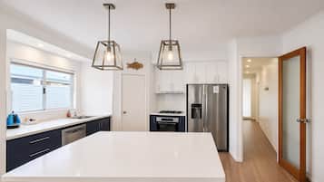 A modern kitchen with a central island, stainless steel appliances, and pendant lighting.