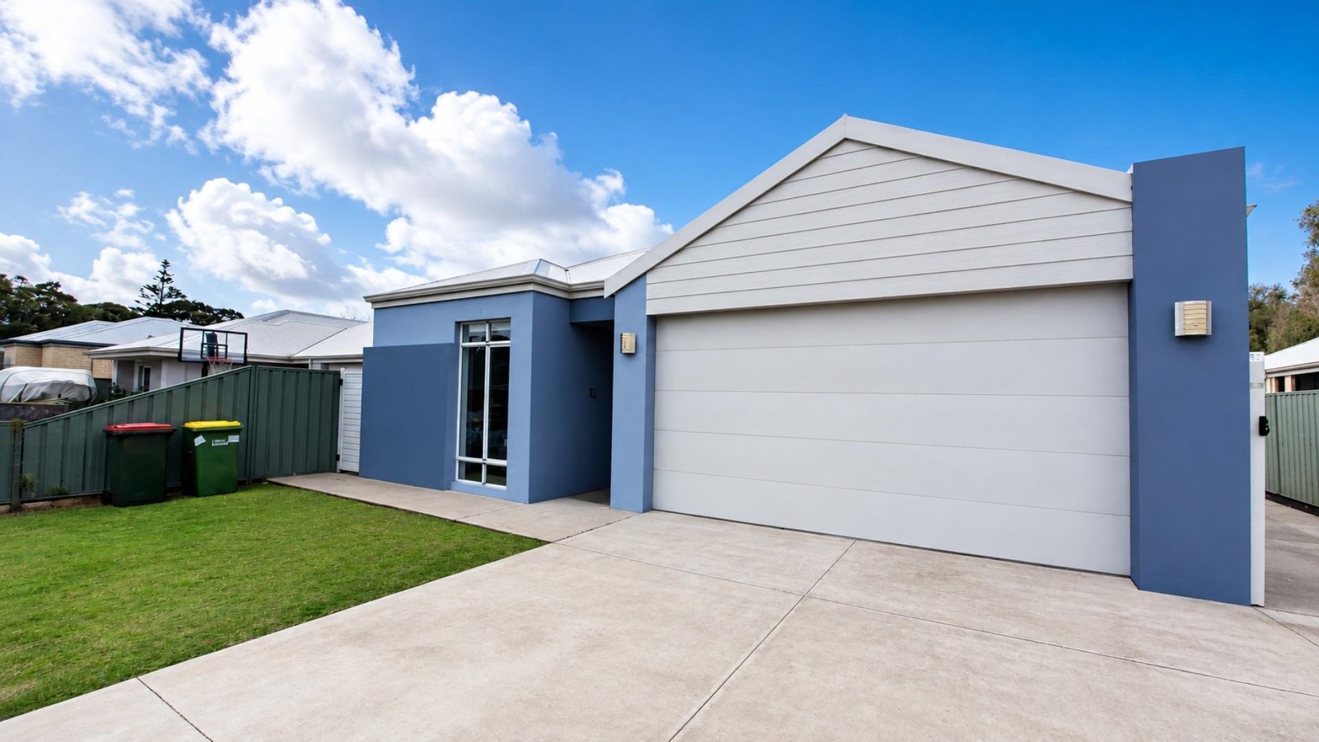 A modern two-story house with a garage, a covered patio, and a well-maintained lawn.