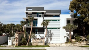 Una casa moderna de dos pisos con techo plano, ventanas grandes y base de piedra.