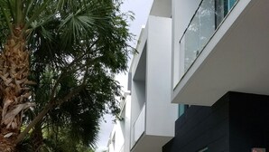 Un edificio moderno con un camino de hormigón, amplias ventanas y una mezcla de vegetación.