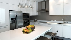 Una cocina moderna con armarios blancos, electrodomésticos de acero inoxidable y una isla central con fruta.