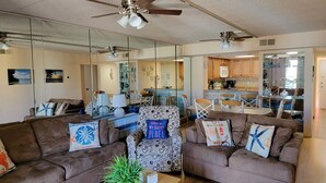 A living room with two brown sofas, a patterned armchair, a coffee table with a plant, and a ceiling fan.
