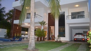 Une maison moderne à deux étages, dotée d’une piscine, d’un espace salon extérieur et d’un garage.