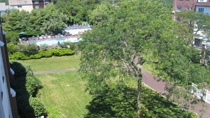 Ein Wohngebiet mit Swimmingpool, gepflegtem Rasen und einem großen Baum, der Schatten spendet.