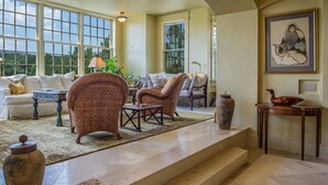 Ein geräumiges Wohnzimmer mit großem Fenster, Kamin und einer Treppe, die zu einer weiteren Ebene führt.
