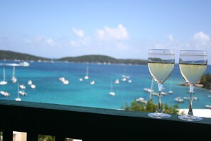 Two wine glasses on a balcony overlooking a marina with boats.