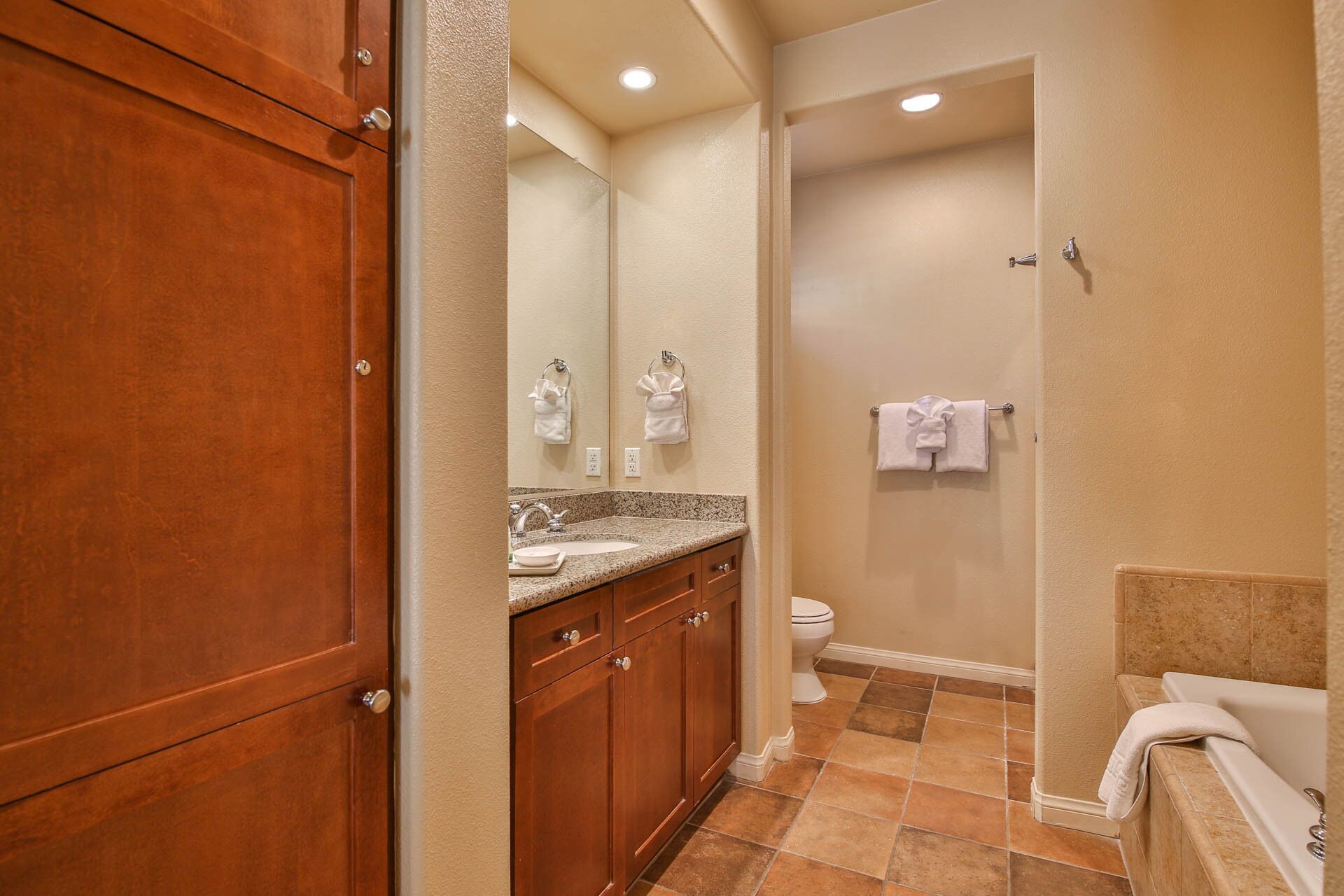 A bathroom with a wooden vanity, a sink, a toilet, and a bathtub.