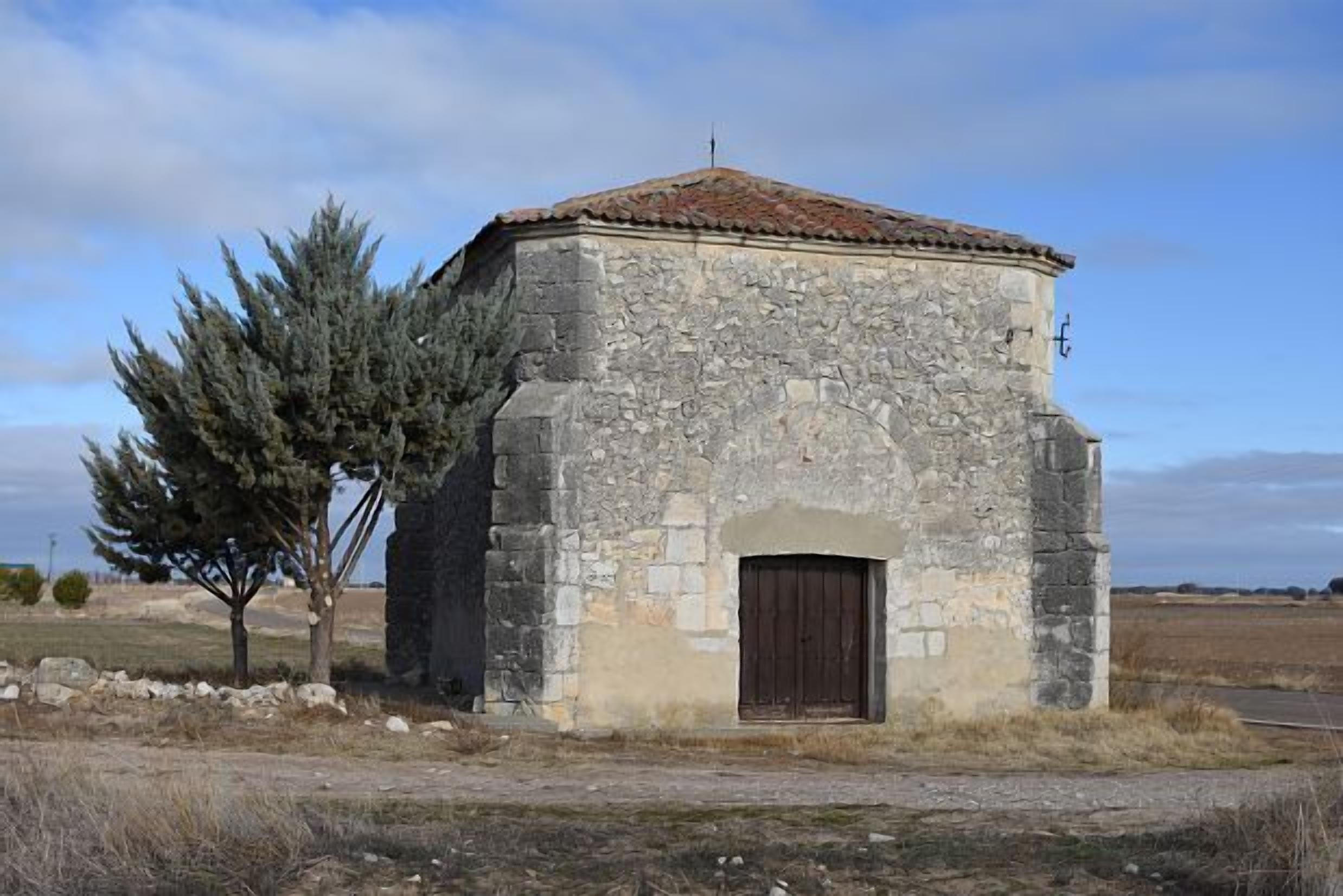 Un pequeño edificio de piedra con techo de tejas y puerta de madera.