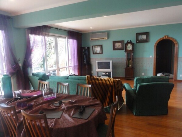 Una sala de estar con una mesa de comedor, sillas, un sofá y una televisión.