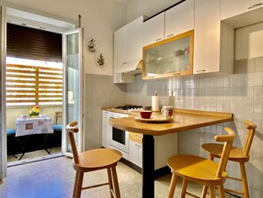 A kitchen with white cabinets, a wooden countertop, and two wooden chairs.