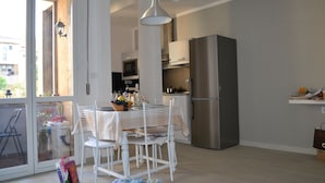 Una cocina moderna con comedor, que incluye un refrigerador de acero inoxidable, un microondas y una mesa de comedor con sillas.